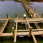 Aerial view of crews framing the new Veterans Memorial Park pier over shallow water in Edgewater