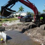 Crew setting precast seawall panels along a Fort Myers Beach canal
