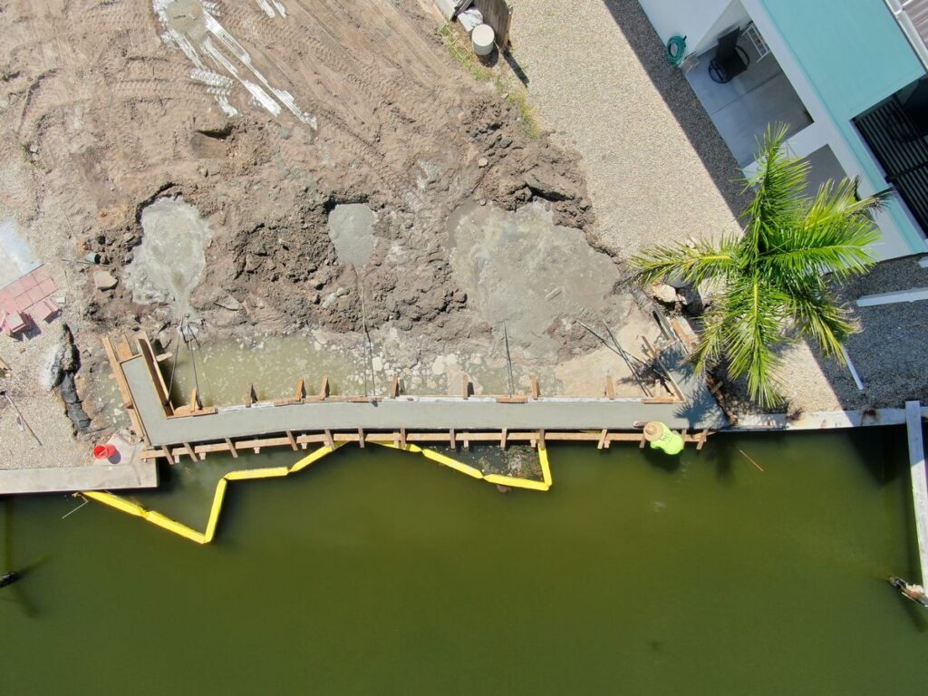 Aerial view of new seawall panels and cap forms with a turbidity barrier on Fort Myers Beach