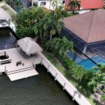 Aerial view of a new dock with tiki hut behind a pool home in southwest Cape Coral