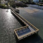 Overhead drone view of the Veterans Memorial Park pier crossing the shallows of the Indian River